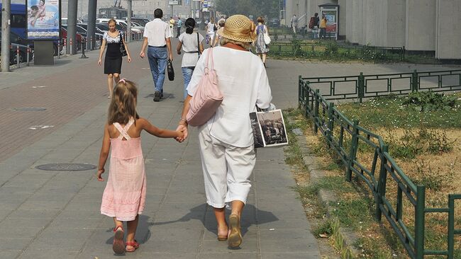 Бубушка с внучкой гуляет по городу. Архив