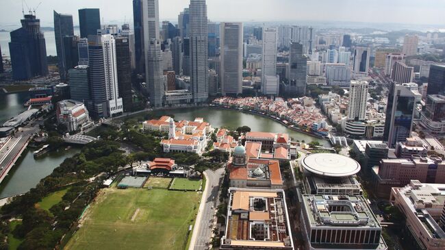 Вид на башни Сити за рекой (Singapore river) и здания старого и нового парламента (на первом плане) в Сингапуре. Архивное фото