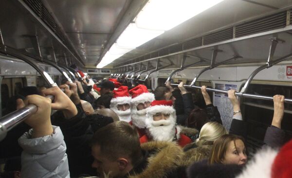Участники предрождественского флешмоба, одетые в костюмы Санта Клаусов, в вагоне метро на Замоскворецкой линии