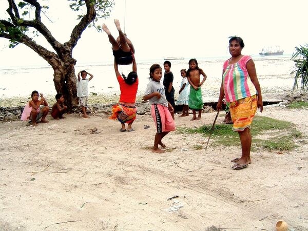 Дети играют на побережье Таравы, атолла в архипелаге Гилберт