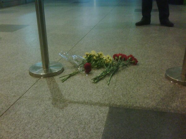 Люди несут живые цветы к месту трагедии в аэропорту Домодедово