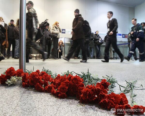 Пассажиры аэровокзала несут цветы к месту трагедии в Домодедово