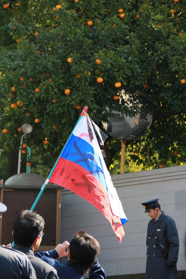 Оскверненный российский флаг в руках у представителя ультраправой организации в Японии