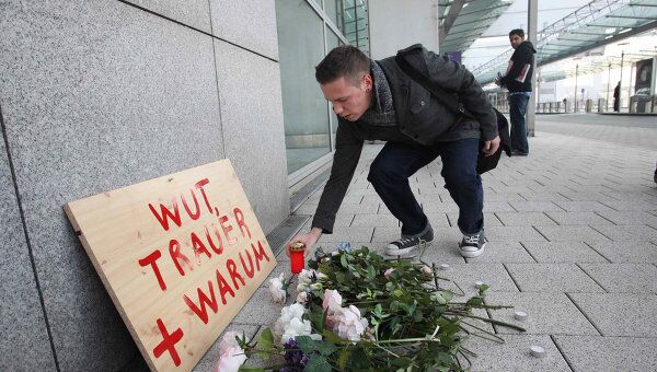Люди кладут цветы возле места убийства в аэропорту Франкфурта