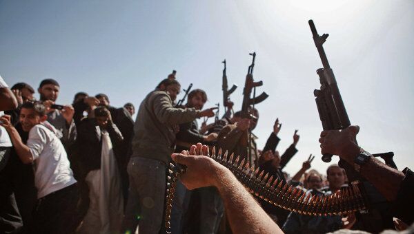Мужчины стреляют в воздух из пулемета во время похорон в память о жертвах атаки наемников Каддафи в городе Адждабия.