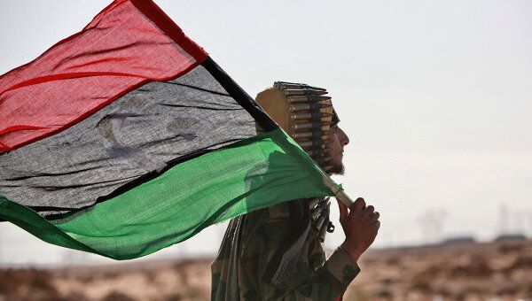 Боец ливийской оппозиции с флагом и пулеметной лентой. Архив
