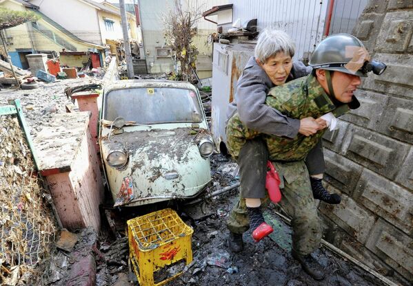 Солдаты сил самообороны Японии эвакуируют жителей из пострадавего от цунами города Kesennuma в префектуре Мияги на северо-востоке Японии, 12 марта 2011.