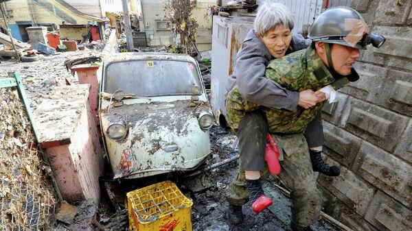 Солдаты сил самообороны Японии эвакуируют жителей из пострадавего от цунами города Kesennuma в префектуре Мияги на северо-востоке Японии, 12 марта 2011.