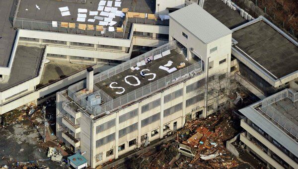Люди ждут помощи на крыше здания после землетрясения в Kesennuma, префектура Мияги 12 марта 2011