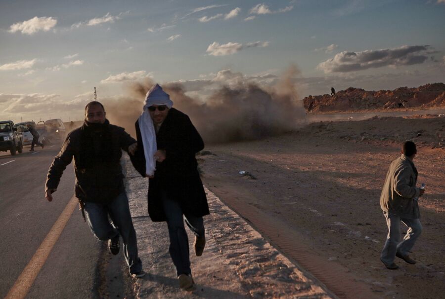Мужчины бегут от взрыва ракеты во время боев за город Бин Джавад