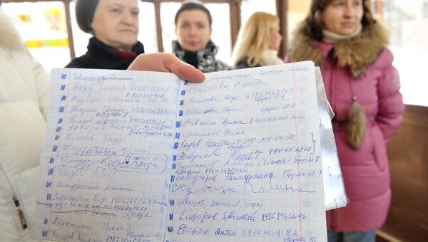 Родители демонстрируют списки детей-кандидатов на зачисление в первый класс одной из московских школ.