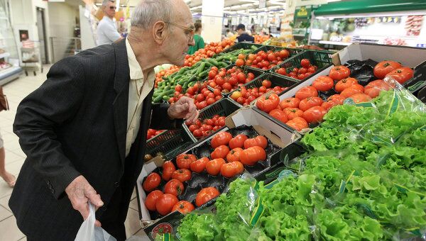 Мужчина выбирает овощи в торговом зале супермаркета Перекресток