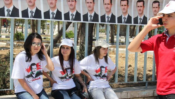 Участница демонстрации отдыхают под портретами президента Башара Асада