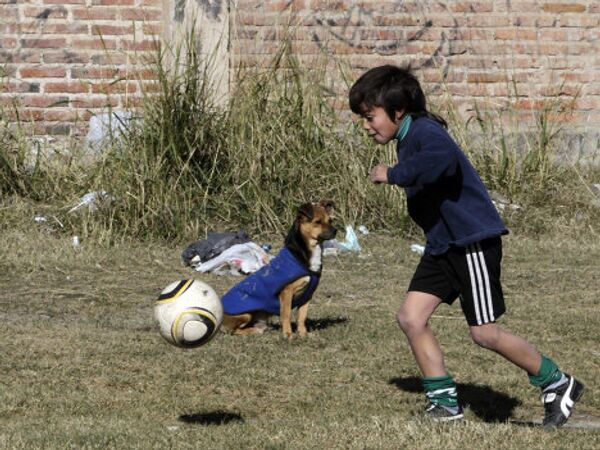 Мальчик играет в футбол с собакой в Санта-Фе