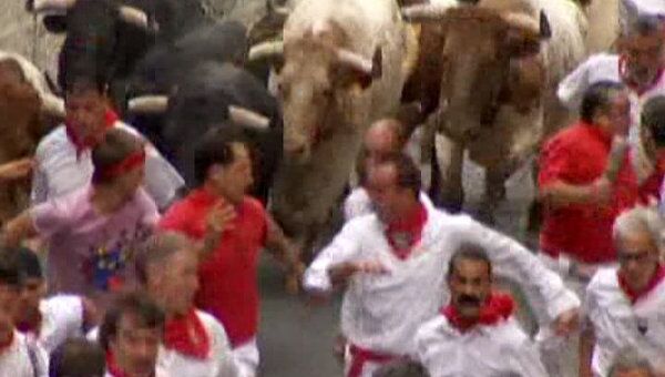 Люди соревнуются с быками в беге на испанском фестивале Сан Фермин