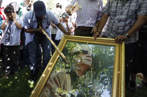 Ливийские демонстранты портят фотографию Муаммара Каддафи