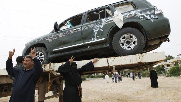 Ливийцы фотографируются рядом с автомобилем, принадлежащим Муамару Каддафи в Мисрате 