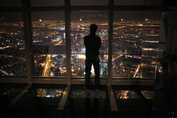 Мужчина стоит у окна в здании Шанхайского финансового центра