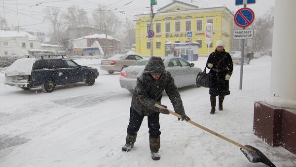 Мужчина убирает снег на центральной улице в Томске