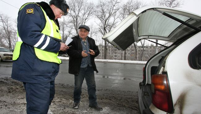 Сотрудник ДПС досматривает багажник автомобиля. Архив