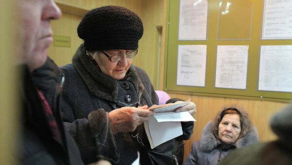Женщина проверяет правильность квитанции за услуги ЖКХ. Архив