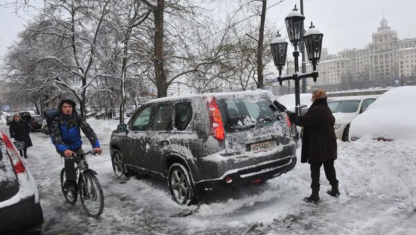 Автовладелец чистит машину от снега, архивное фото