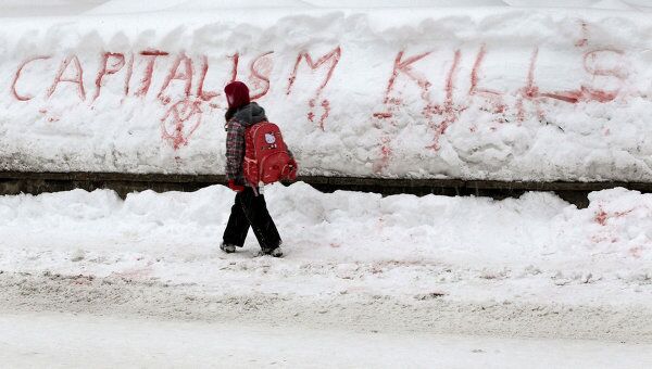 Девушка проходит мимо лозунга, написанного на снегу противниками форума в Давосе