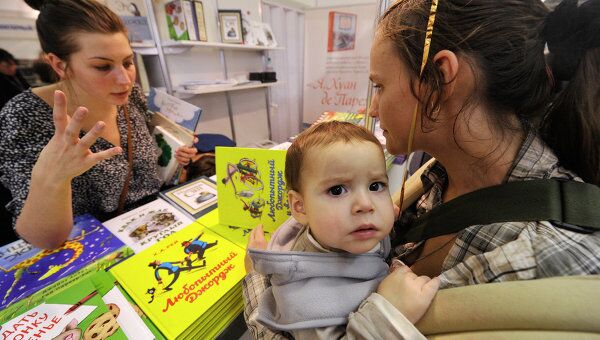 Посетительница с ребенком знакомится с книжными новинками для детей