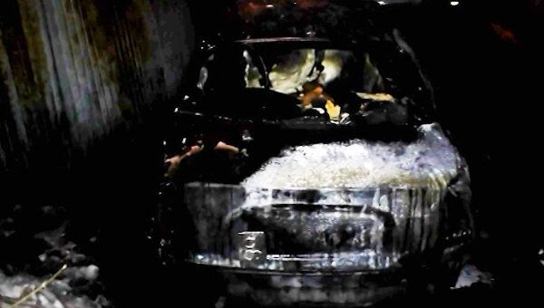 Обугленный автомобиль дымится после поджога неизвестным в Москве