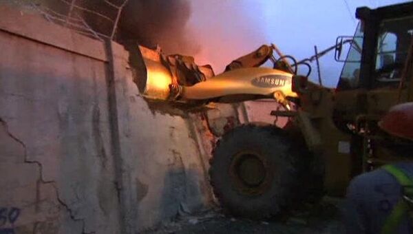 Бетонный забор ломают трактором, чтобы потушить горящие дома в Маниле
