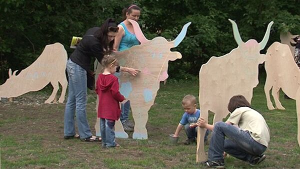 Дети раскрашивают фанерных коров на Зеленой неделе в парке Горького