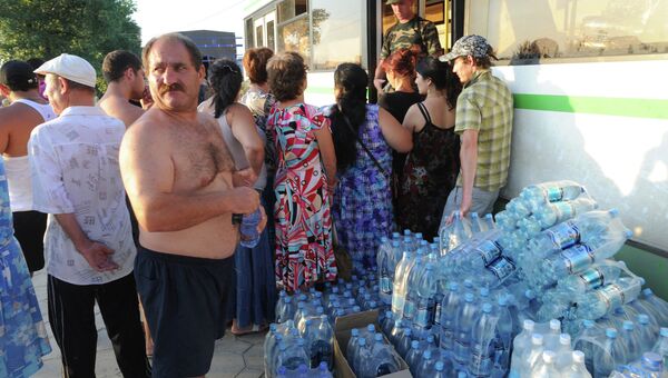 Жители пострадавшего от наводнения города Крымска получают пресную воду в пункте раздачи гуманитарной помощи.