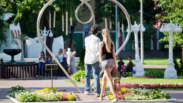 Влюбленная пара проходит через памятник Сердце в саду Эрмитаж