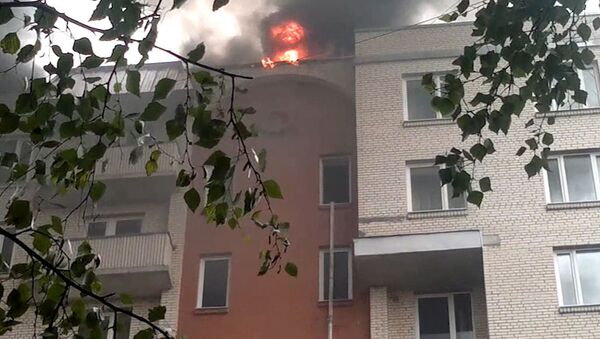 Пламя и дым вырываются из крыши многоэтажного дома в Санкт-Петербурге