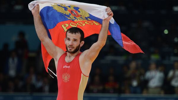 Российский борец Джамал Отарсултанов, завоевавший золотую медаль, с российским флагом после победы в финальном поединке