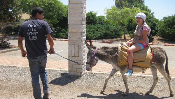 Туристка катается на осле в израильском парке Кфар Кедем
