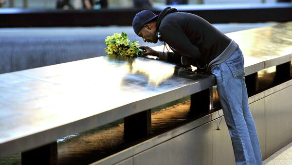 Мужчина кладет цветы на мемориальную плиту в Нью-Йорке в честь памяти жертв теракта 11 сентября