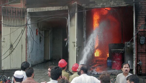 Пожарные тушат пожар на швейной фабрике в городе Карачи, Пакистан