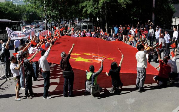 Демонстранты держат флаг Китая возле японского посольства в Пекине
