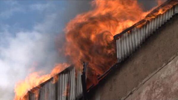 Пламя вырывалось из-под крыши двухэтажного горящего здания в Барнауле