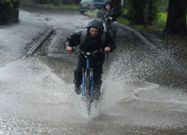 Ребята катаются на велосипедах по лужам во время наводнения в городе Морпет в Великобритании