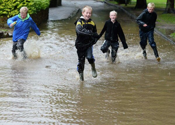 Ребята бегают по лужам во время наводнения в городе Морпет в Великобритании