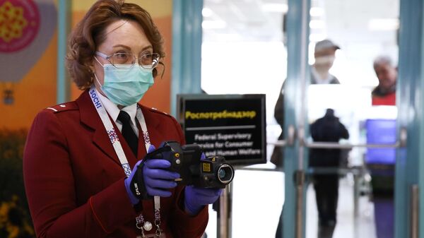 Сотрудник санитарно-карантинного пункта проводит дистанционную термометрию пассажиров, прибывших в международный аэропорт Краснодар