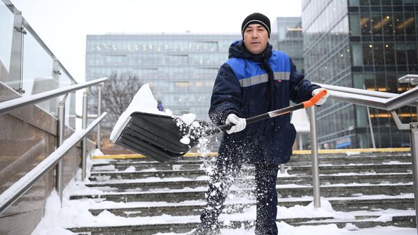 Сотрудник коммунальной службы чистит лестницу от снега в Москве