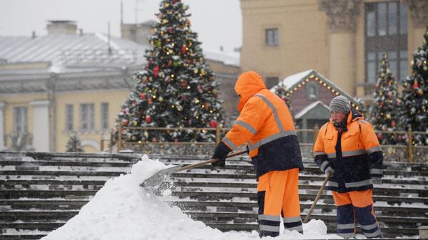Сотрудники коммунальной службы чистят тротуары от снега в Москве