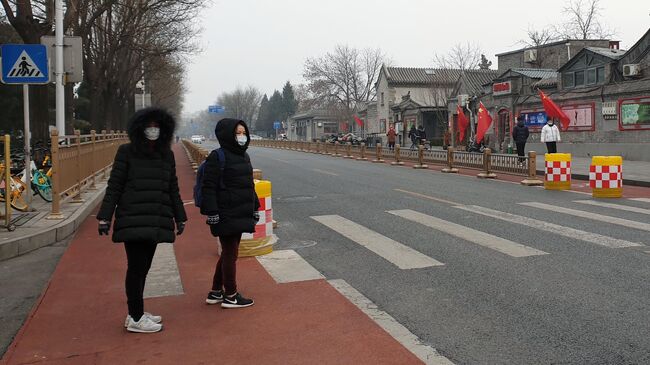 Женщины в медицинских масках переходят улицу в Пекине