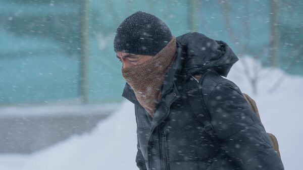 Мужчина идет по улице во время снежной метели в Нур-Султане.