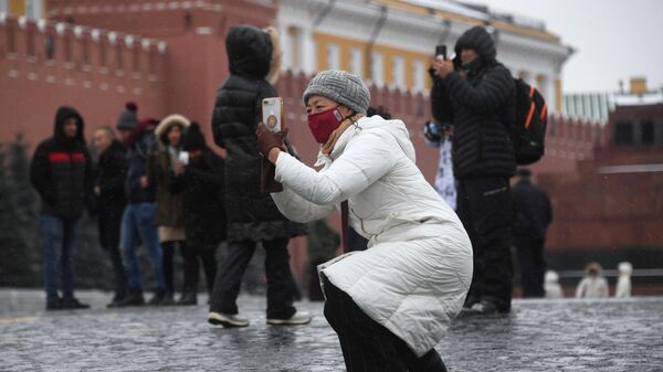 Иностранные туристы в защитных масках на Красной площади в Москве