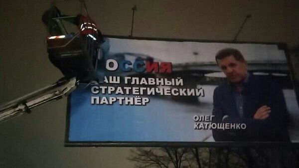 Работники коммунальных служб во время демонтажа в Киеве рекламного плаката с надписью Россия - наш главный стратегический партнер