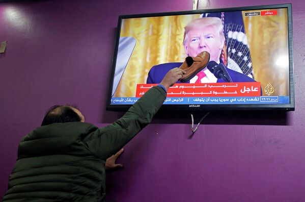 Палестинец смотрит выступление президента США Дональда Трампа по урегулированию палестино-израильского конфликта в кафе Хеврона